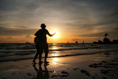 Silhouette man on beach against sky during sunset