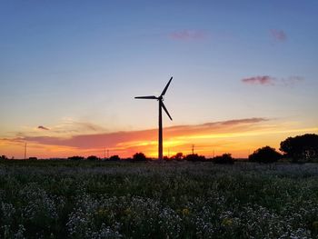 Wind turbines on field against sky during sunset