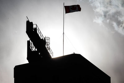 Low angle view of silhouette crane against sky