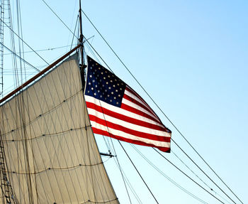 Low angle view of american flag on mast against clear blue sky