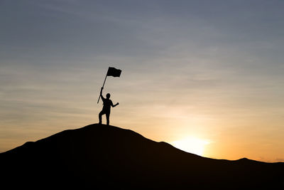 Silhouette man standing on mountain against sky during sunset