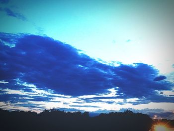 Low angle view of silhouette trees against blue sky