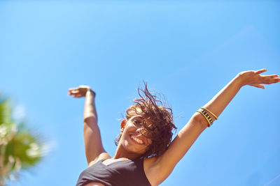 Portrait of smiling woman dancing against clear sky