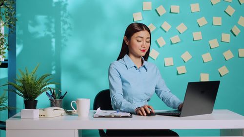 Portrait of young woman using laptop while sitting on table