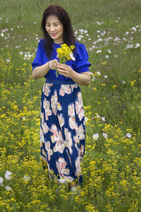 Young woman standing by yellow flower on field