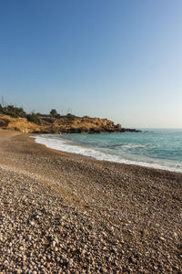 Surface level of beach against clear blue sky