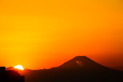 Scenic view of silhouette mountains against orange sky