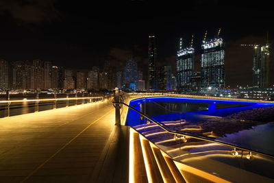 Light trails on road by illuminated buildings in city at night