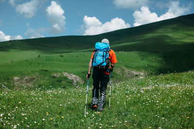 Low angle view of male hiker hiking on grassy mountain