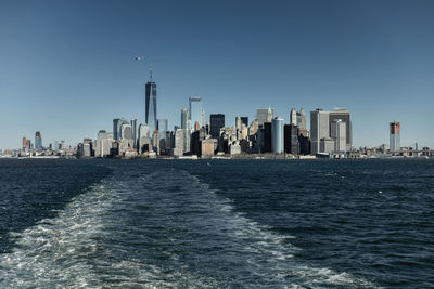 City at waterfront against clear blue sky