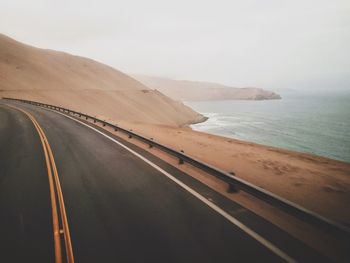 High angle view of empty road by sea against clear sky