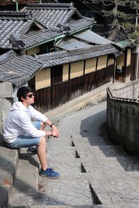 Young man sitting on steps against building