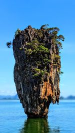 Rock formation in sea against clear blue sky