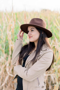 Young woman looking away while standing on field