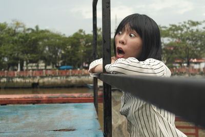 Portrait of teenage girl sitting by railing