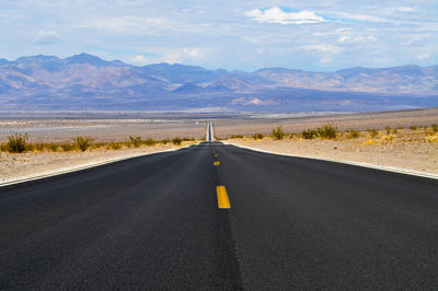 Road by mountains against sky