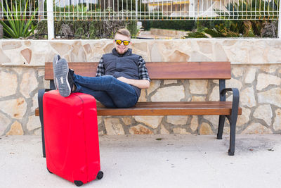 Man sitting on bench against wall