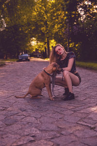 Portrait of young woman with dog sitting on tree