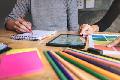 Close-up of people working over color swatch in office