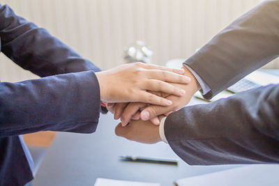 Cropped hands of business coworkers stacking hands in office