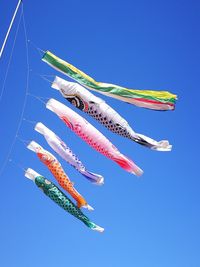 Low angle view of colorful flags against clear blue sky