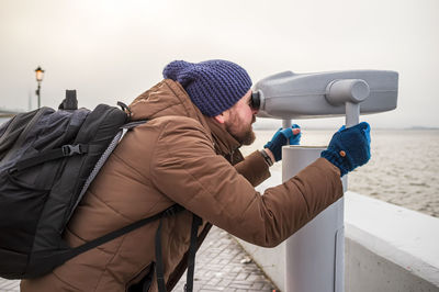 Side view of man with umbrella standing in winter