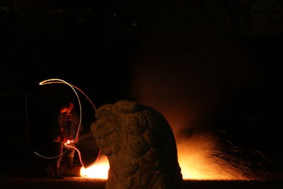 Close-up of burning statue against dark background
