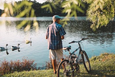 Rear view of man on bicycle by lake