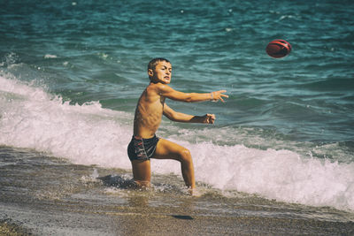 Boy throwing ball on beach