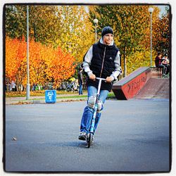 Full length of boy riding skateboard on road