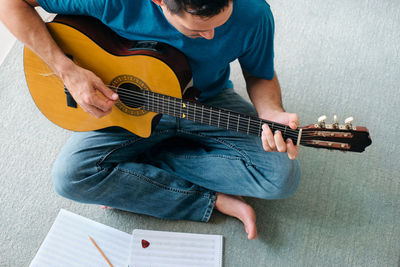 Midsection of man playing guitar against wall