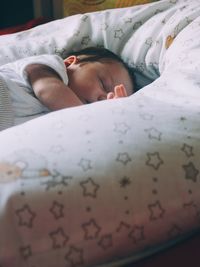 Close-up of baby sleeping on bed at home