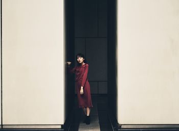 Portrait of woman standing against wall