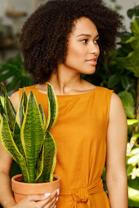 Thoughtful young woman holding potted plant