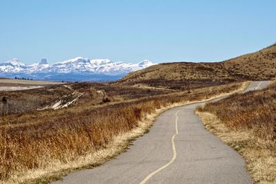 Scenic view of road by mountains against blue sky