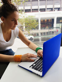 Concentrated woman using laptop by glass window