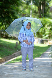 Full length of boy holding umbrella standing on rainy day