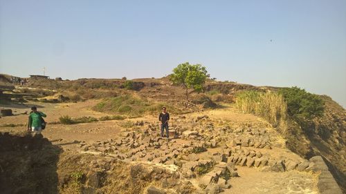 Rear view of men standing on land against clear sky