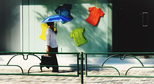 Woman holding smart phone while standing on umbrella