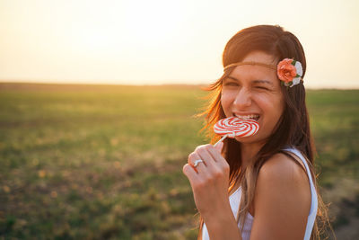 Portrait of young woman eating lollipop during sunset