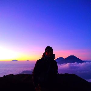 Silhouette man standing on mountain against sky during sunset