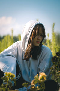 Beautiful woman standing by flowering plants against sky