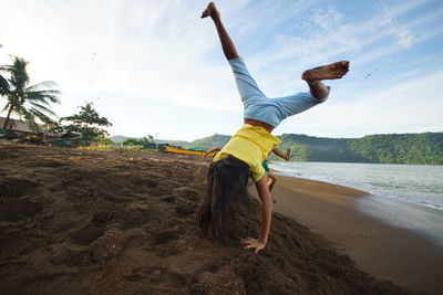 Full length of girl doing handstand at beach