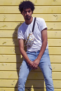 Portrait of young man standing against wall