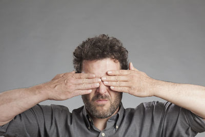 Close-up of man with hand against gray background