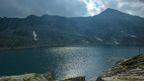 Scenic view of lake by mountains against sky