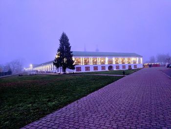 Park by illuminated street against sky at night