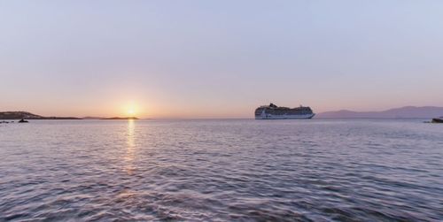 Boat sailing in sea against clear sky during sunset