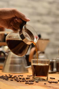 Close-up of hand pouring coffee in cup