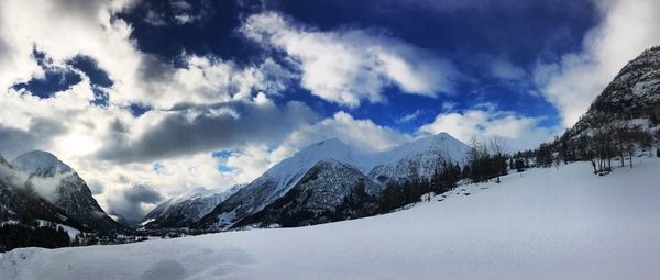 Scenic view of snow covered mountains against cloudy sky